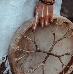 a close up of a person's hand holding a drum with white paint on it