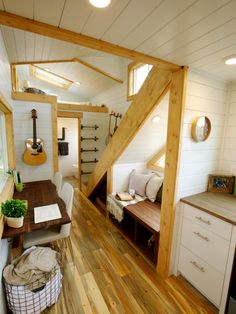 the interior of a tiny home with wood floors and white walls, stairs leading up to an upstairs loft