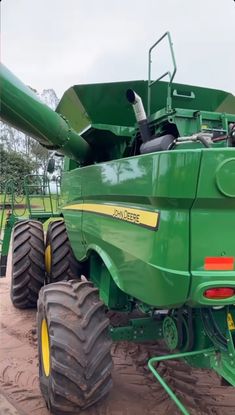 a large green tractor parked on top of a dirt field