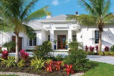 a white house surrounded by palm trees and flowers