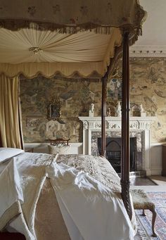 a bedroom with a canopy bed, fireplace and tapestryed wallpaper on the walls