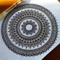 a pen is sitting on top of a paper with an intricate design in the middle