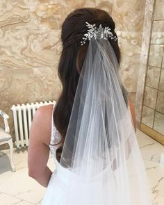 a woman in a wedding dress looking at herself in the mirror while wearing a veil