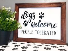 a sign that says dogs welcome people tolerrated next to a potted plant