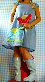 a woman in boots and dress standing on a red stool with her legs crossed up