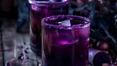 two glasses filled with purple liquid on top of a table