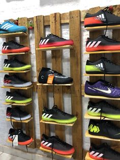 several pairs of adidas shoes are on display in a shoe store with wooden pallets