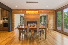 a dining room with wood floors and large windows