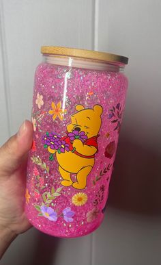 a hand holding a pink winnie the pooh tumbler