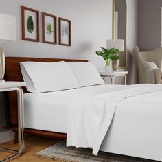 a bed with white sheets and pillows in a room