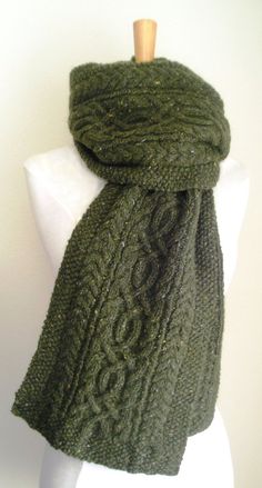 a green knitted scarf sitting on top of a white mannequin