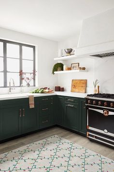 a kitchen with green cabinets and an oven in the center, along with a rug on the floor