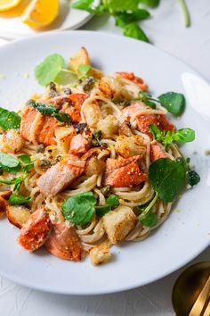 a white plate topped with pasta covered in lobster and spinach garnished with parsley