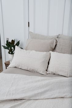 a bed with two pillows on top of it next to a potted green plant