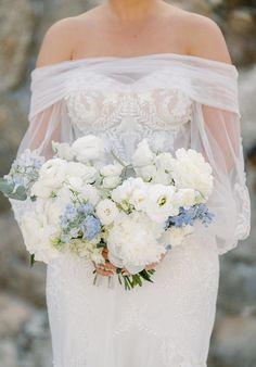 bride holding white and soft blue lush garden inspired bouquet of peony, rose, ranunculus, delphinium Blue White Green Bridal Bouquet, White And Pastel Bridal Bouquet, Classic Wedding Flowers Bridal Bouquets, Coastal Bouquet Wedding, White And Light Blue Bridal Bouquet, Bridal Bouquet Light Blue, White Blue Wedding Bouquet, White Green And Blue Bridal Bouquet, Bridal Bouquet White And Blue