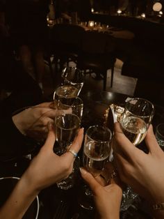 several people are toasting with wine glasses on a table in a dimly lit room