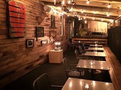 the inside of a restaurant with wooden walls and tables, lit up by string lights