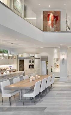 a large dining room table with white chairs and an open floor plan in the background