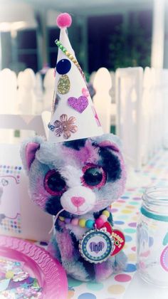 a stuffed animal with a party hat on it's head sitting at a table