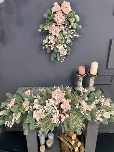 two wreaths are hanging on the wall next to a fireplace with candles and flowers