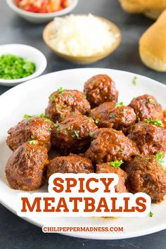 spicy meatballs on a white plate with green garnish and rice in the background