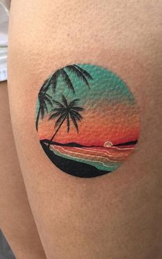 a woman's thigh with a sunset and two palm trees on it, in the shape of a circle