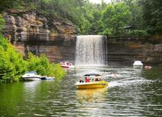 several boats floating in the water near a waterfall