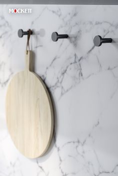 a wooden cutting board mounted to the side of a white marble counter top with black handles