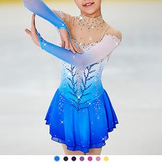 a woman in a blue and white figure skating outfit with her arms extended up to the side