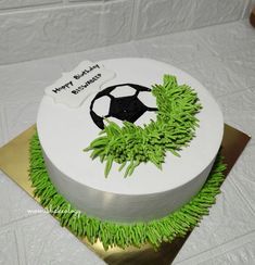 a soccer themed birthday cake with green grass around the edges and a soccer ball on top