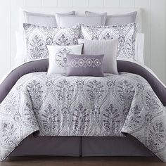 a white and grey bed with pillows on it