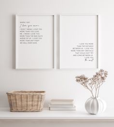 two framed pictures on the wall above a shelf with books and flowers in a vase