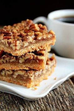 three pieces of granola on a white plate with a cup of coffee in the background