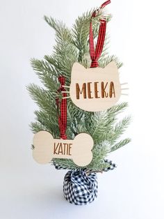 a christmas tree with two wooden tags hanging from it's branches and the words meka written on them