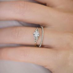 a woman's hand with a diamond ring on top of her finger and an engagement band