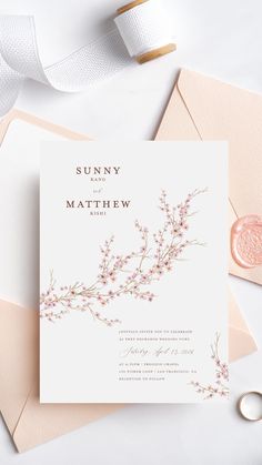 the wedding stationery is laid out on top of pink envelopes