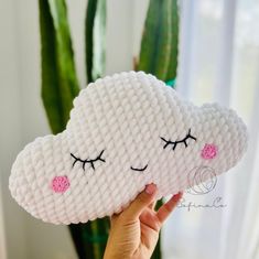 a hand holding up a pillow shaped like a cloud