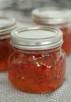 four jars filled with pickles sitting on top of a table