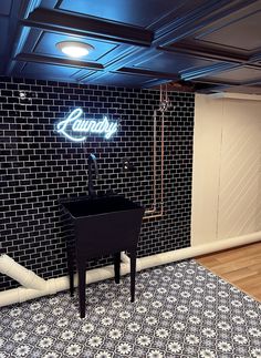 a black and white tiled room with a neon sign on the wall