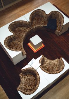 an animal print couch and chair on top of a white table with wooden flooring