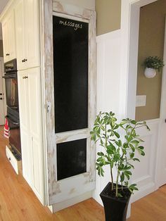 a potted plant sitting in front of a chalkboard on the door to a kitchen