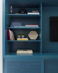 a blue bookcase with books and a television on it