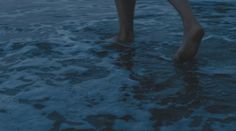 a person walking in the water with their bare feet sticking out from the water at dusk