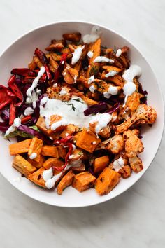 a white bowl filled with lots of food on top of a marble countertop next to a knife and fork