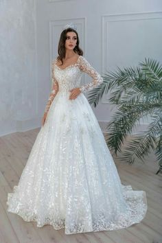 a woman in a white wedding dress standing on a wooden floor wearing a tiara