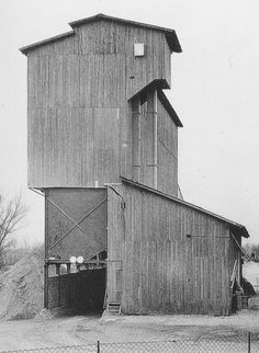 an old photo of a grain silo in black and white with the door open