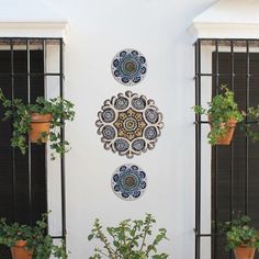 an outdoor area with potted plants and decorative wall hangings on the side of the building