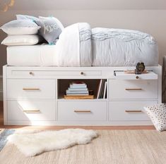 a white bed with lots of drawers underneath it