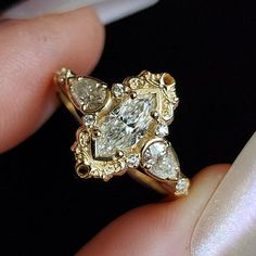 a close up of a person holding a gold ring with diamonds on it's sides