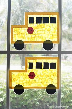 two pieces of paper cut out to look like school buses on a window sill